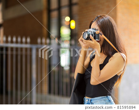 Female freelancer photographer taking picture with film camera 81595894