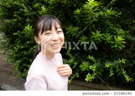 A woman touching a silver accessory necklace with her hand on her chest in the green garden A woman touching a silver accessory necklace with her hand on her chest in the green garden 81596240