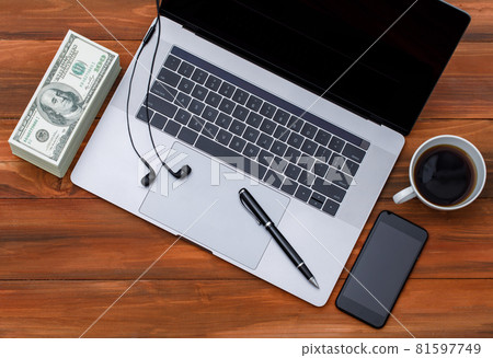 Topview or top down shot of laptop notebook computer with black coffee in white cup on wood background with pile of dollar money banknotes 81597749