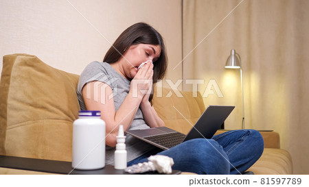 Young woman with long loose hair sneezes into paper napkin 81597789