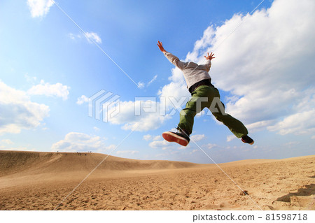 Back view of a man jumping in the Tottori Sand Dunes, Japan 81598718