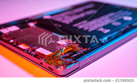 Unrecognizable man disassembles laptop with screwdriver in muted red and blue light Unrecognizable man disassembles laptop with screwdriver in muted red and blue light 81598920