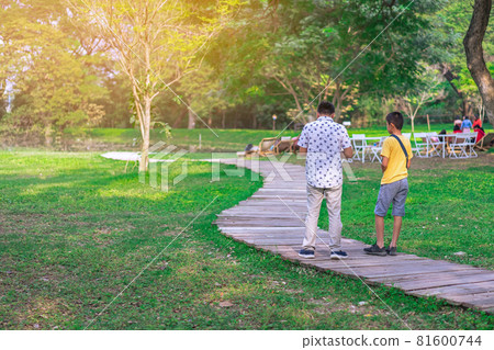 Back view of Asian father and son walking on pathway through green garden.Dad and son walking together in park. Happy family spending time together outside in green nature. Family time concept. 81600744
