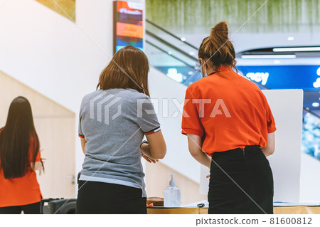 Back view of female customer wear face mask register her identity by using QR code via SafeEntry to check-in or registration book before shopping during the outbreak of Corona virus (Covid-19). 81600812