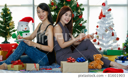Cheerful Asian women with notebooks near Christmas trees Cheerful Asian women with notebooks near Christmas trees 81601903