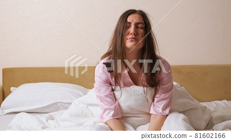Sleeping dark haired woman in pajama rises quickly upset Sleeping dark haired woman in pajama rises quickly upset 81602166