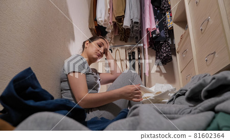 Upset maid looks at dirty laundry on floor in walk-in closet 81602364