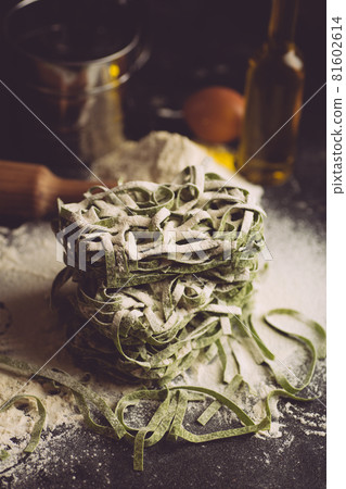 Italian pasta food background. Vegan italian pasta fresh with spinach - Spinach Fettuccine Alfredo Pasta on a dark background. Old kitchen background. Copy space 81602614