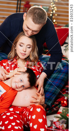 beautiful happy family in pajamas in the New Year's bedroom. pregnancy beautiful happy family in pajamas in the New Year's bedroom. pregnancy 81603243