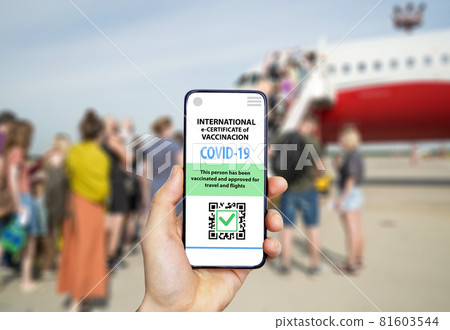 Coronavirus vaccination certificate or vaccine passport for travellers concept. COVID-19 immunity e-passport in the smartphone mobile app for international travelling. Hand with a phone on the 81603544
