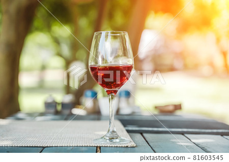 A glass of red wine on the table of a street cafe a sunny summer day. Summer, lifestyle, relaxation, and enjoyment concept. 81603545