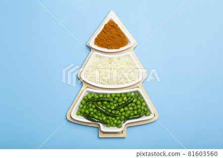 Indian flag in the shape of a new year christmas tree made from food background. Basmati rice, curry, green peas and chili peppers in the colors of the Indian flag and Christmas tree on a blue Indian flag in the shape of a new year christmas tree made from food background. Basmati rice, curry, green peas and chili peppers in the colors of the Indian flag and Christmas tree on a blue 81603560