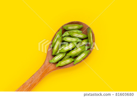 Fruit of Broken Bone tree slices in wooden spoon on yellow background. Fruit of Broken Bone tree slices in wooden spoon on yellow background. 81603680
