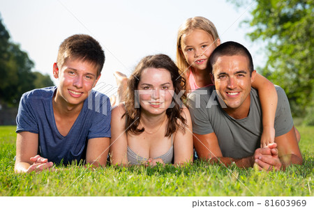 Happy parents with two kids laying on grass in sunny summer park Happy parents with two kids laying on grass in sunny summer park 81603969