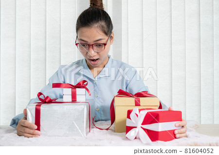 Asian woman holding a gift box Glad to be the giver of surprise with excitement, joy, and smiles on the holidays, Christmas, birthdays, or Valentine's Day concept 81604052