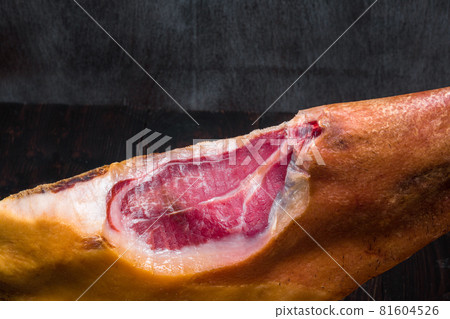 Part of mediterranean traditional jamon on a wooden stand with a knife lean on a table. Dark image Part of mediterranean traditional jamon on a wooden stand with a knife lean on a table. Dark image 81604526