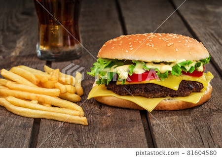 Fast food. Cheeseburger and french fries on a wooden background Fast food. Cheeseburger and french fries on a wooden background 81604580