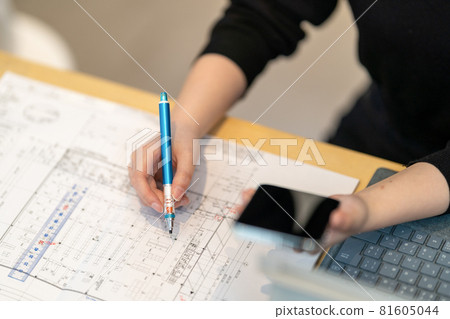 Female first-class architect who draws drawings while looking at a mobile phone 81605044