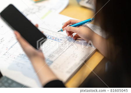 Female first-class architect who draws drawings while looking at a mobile phone 81605045