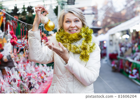 Adult woman is choosing decorations for Christmas tree in the market Adult woman is choosing decorations for Christmas tree in the market 81606204