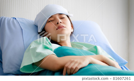 An asian young beautiful female patient getting sick, lying and sleeping on bed in hospital with cool pack on her forehead to relieve the fever. Medical Treatment and Health concept. 81607261
