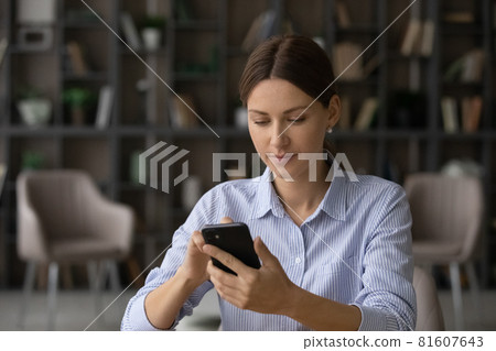 Focused businesswoman looking at phone screen, browsing mobile device apps 81607643