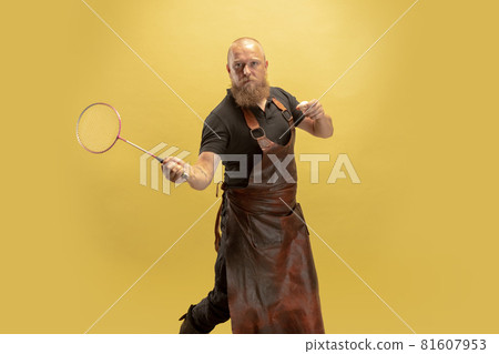 Comic portrait of muscular bearded bald man, blacksmith in leather apron or uniform isolated on yellow studio background. Concept of labor, retro professions, power, strength, humor 81607953