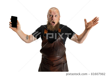 Comic portrait of muscular bearded bald man, blacksmith in leather apron or uniform isolated on white studio background. Concept of labor, retro professions, power, beauty, humor Comic portrait of muscular bearded bald man, blacksmith in leather apron or uniform isolated on white studio background. Concept of labor, retro professions, power, beauty, humor 81607982