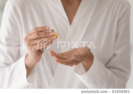 Close up young woman in bathrobe applying serum. Close up young woman in bathrobe applying serum. 81608961