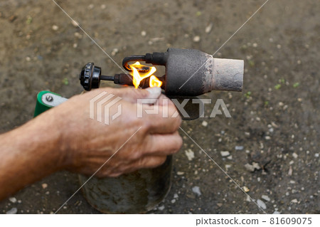 A man kindles a flame at the old rusty blowtorch. A man kindles a flame at the old rusty blowtorch. 81609075