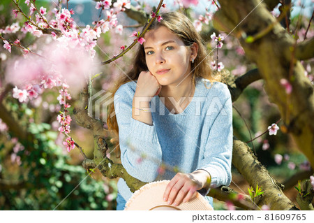 Positive smiling girl posing in blooming garden 81609765