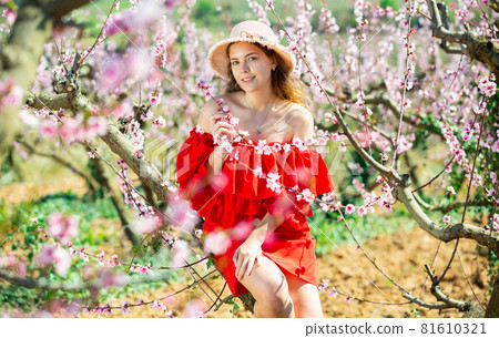 Young girl standing in spring blooming garden 81610321