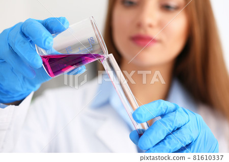 Female chemist holds test tube of glass in his hand overflows a liquid Female chemist holds test tube of glass in his hand overflows a liquid 81610337