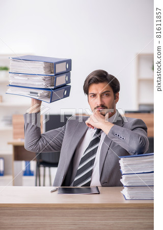 Young male employee unhappy with excessive work in the office Young male employee unhappy with excessive work in the office 81611857
