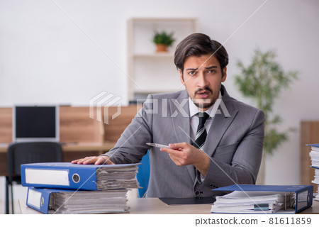 Young male employee unhappy with excessive work in the office 81611859