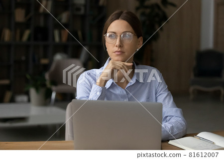 Thoughtful woman in glasses looking to aside, distracted from laptop 81612007