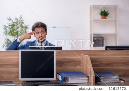 Young male employee sitting at workplace Young male employee sitting at workplace 81612570