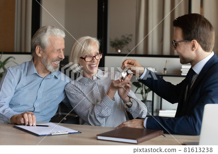 Businessman manager giving keys to excited mature couple at meeting 81613238