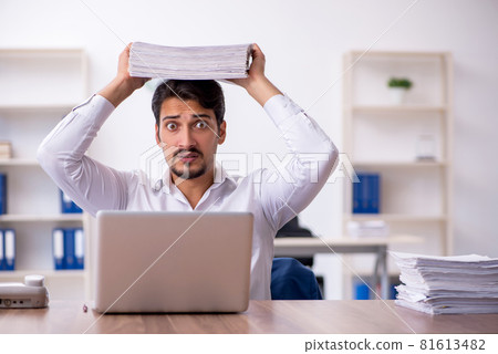 Young male employee and too much work in the office 81613482