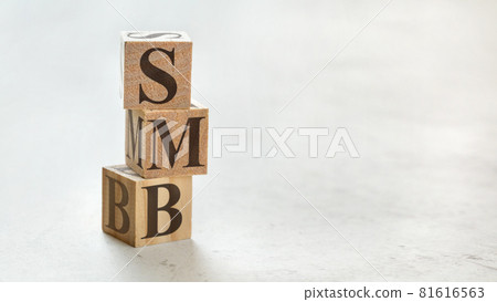 Pile with three wooden cubes - letters SMB meaning Small to medium sized business on them, space for more text / images at right side. 81616563