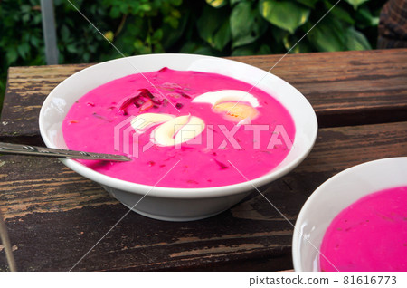 Cold beetroot soup with egg and sour cream in plates on wooden table. Cold beetroot soup with egg and sour cream in plates on wooden table. 81616773
