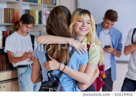Two school girlfriends teenagers are welcome, meeting, smiling, rejoicing inside school 81619402
