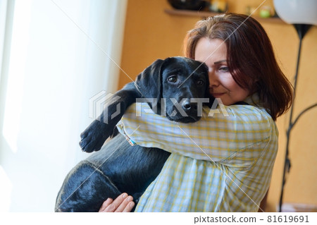Portrait of middle aged woman and black labrador puppy dog 81619691