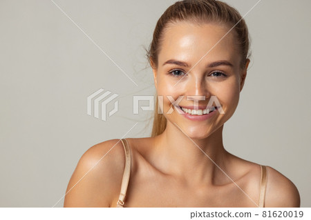 Close-up vertical portrait of young smiling beautiful woman isolated over pastel gray studio background Close-up vertical portrait of young smiling beautiful woman isolated over pastel gray studio background 81620019