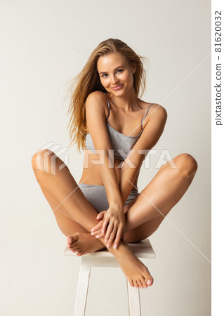 Full-length portrait of young caucasian woman in gray inner wear isolated over light studio background 81620032