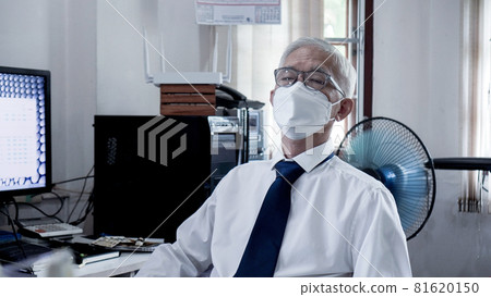 Asian senior elder man working on computer exhaustly at work from home office wearning mask and glasses Asian senior elder man working on computer exhaustly at work from home office wearning mask and glasses 81620150