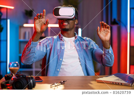 African man using VR glasses and laptop for remote work African man using VR glasses and laptop for remote work 81620739