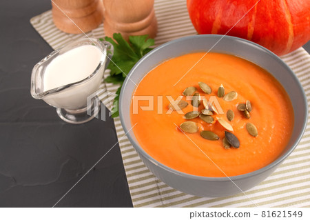 Pumpkin cream soup in gray bowl toped with pumpkin seeds on gray table background with copy space for text. Vegan food concept, homemade soup recipe. Autumn food. Selective focus Pumpkin cream soup in gray bowl toped with pumpkin seeds on gray table background with copy space for text. Vegan food concept, homemade soup recipe. Autumn food. Selective focus 81621549