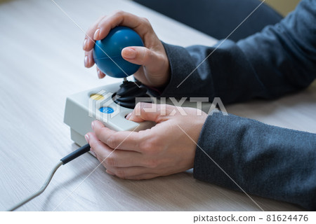 Woman with cerebral palsy works on a specialized computer mouse. Woman with cerebral palsy works on a specialized computer mouse. 81624476