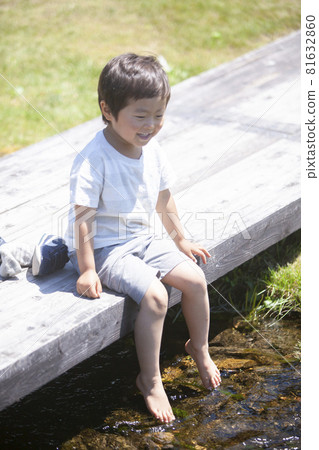 A boy putting his foot on a stream 81632860